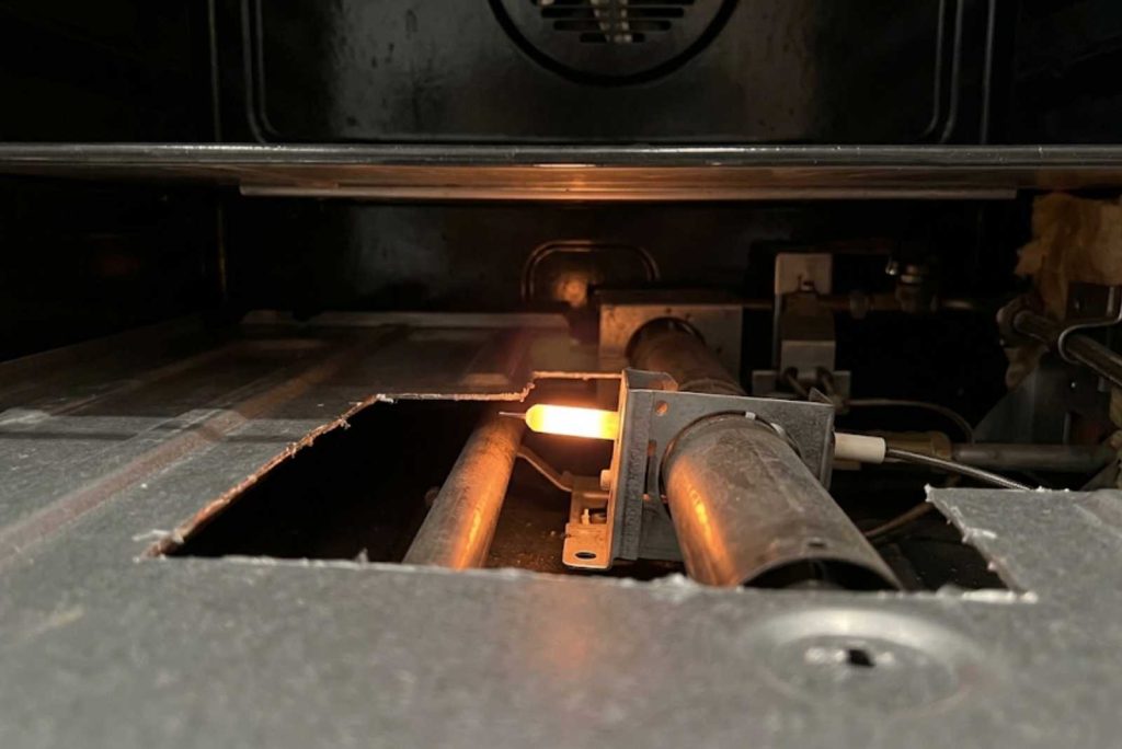 Glowing hot-surface igniter under a GE Monogram gas oven floor